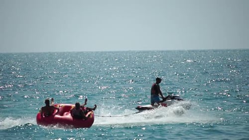 Jet Ski Tows Raft of People on Ocean
