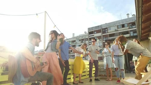 Friends Dancing and Playing Guitar on Rooftop Party