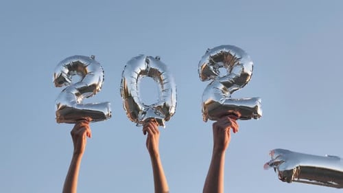 People Holding Silver 2022 Balloons in the Sky