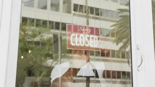 Sad african american male barista wearing black apron turning sign and closing cafe