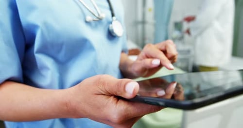 Mid section of female doctor using digital tablet