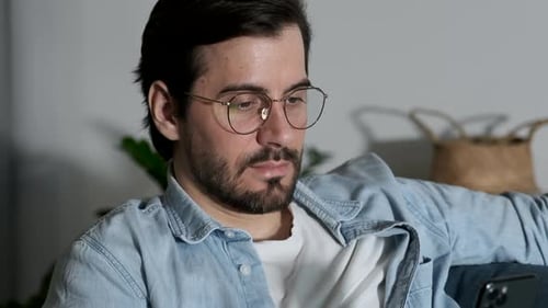 Close-up Portrait of A young man with Glasses Looking at a Smartphone, Online Applications