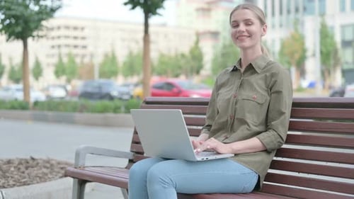 Woman Uses Laptop on Bench in City Park
