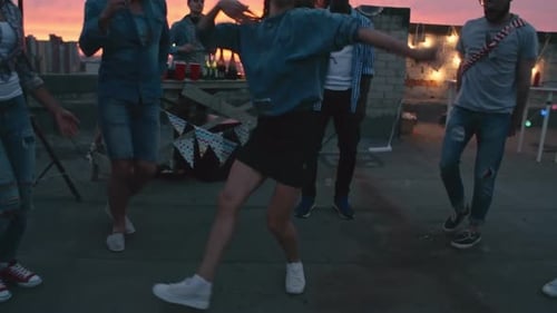 Young Adults Dancing on City Rooftop at Sunset