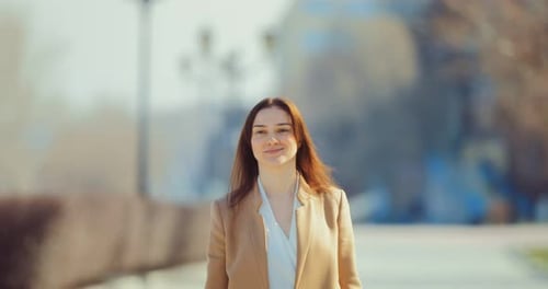 Young Brunette Woman is Walking Along the Spring Street the Girl is Happy