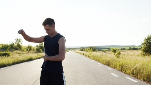 Man Stretching on Rural Road in Sunlight