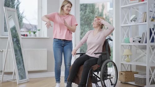 Plan large d'une jeune femme joyeuse dansant avec une amie handicapée à l'intérieur