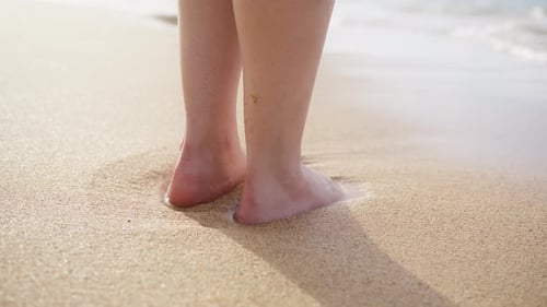Feet Standing in Waves on Sandy Beach
