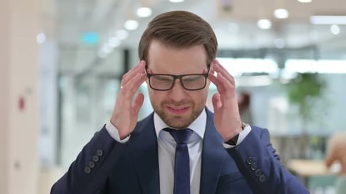 Businessman Rubbing Temples Suffering From Headache Pain