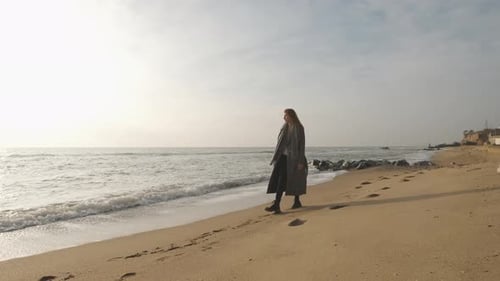 Attractive Redhead Woman in Coat Walking on the Wild Autumn Beach