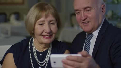 Senior Couple Looking at Phone Together and Smiling