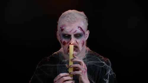 Man in Zombie Makeup Holds Lit Candle
