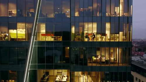 Office Building at Night with People Working Inside the Night Skyscraper