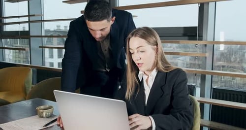 Portrait of a Man and a Woman Discussing Work with Notebook in the Brightly Lit Modern Office