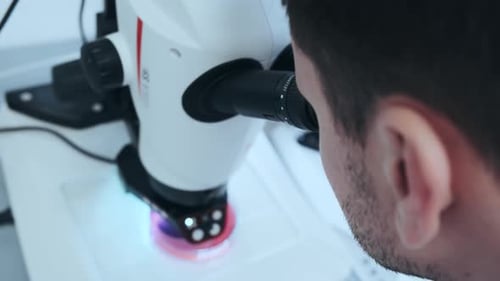 Jovem cientista olhando através de um microscópio em um laboratório
