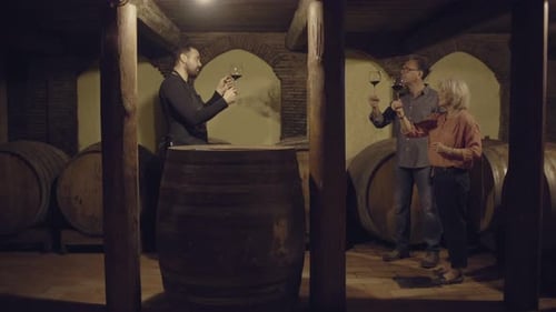 People Tasting Red Wine in Dark Wine Cellar