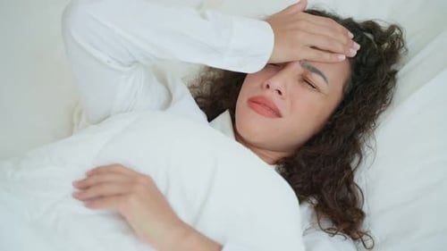 Woman Lying in Bed Suffering from Headache