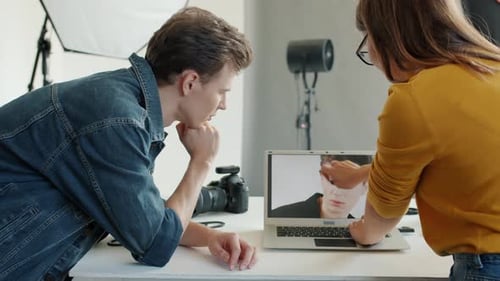 Slow Motion of Model and Photographer Watching Photographs on Laptop in Studio