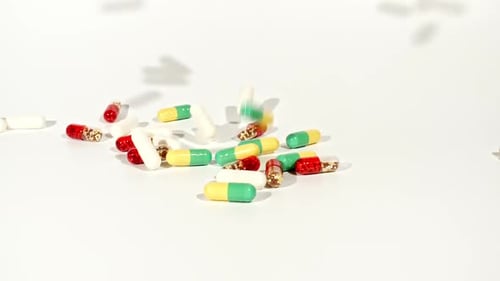 Closeup of Different Medical Pills Falling on Table on White Background