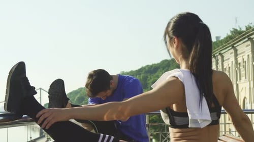 Young Athletic Couple Stretching Together Outdoors Before Morning Run