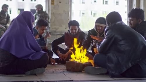 Refugiados sentados junto al fuego en un edificio abandonado