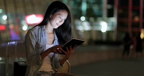 Woman Using Tablet at Night in the City
