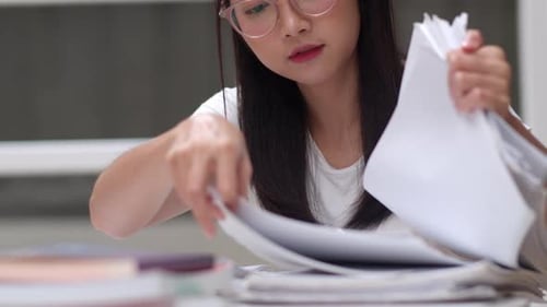 Young Adult Sorting Paperwork at Desk Indoors