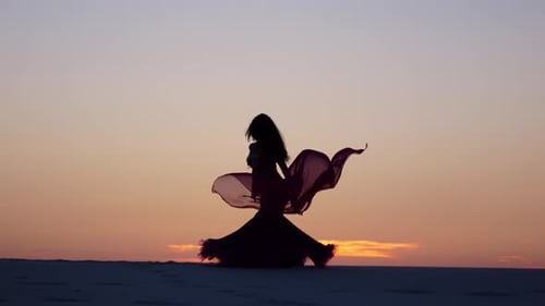 Silhouette of Woman Dancing in Desert at Sunset