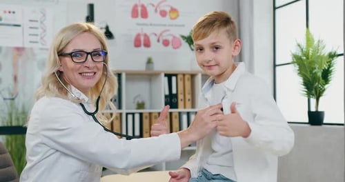 Une femme médecin vérifie les poumons d'un adolescent et ils font ensemble un bon travail devant la caméra