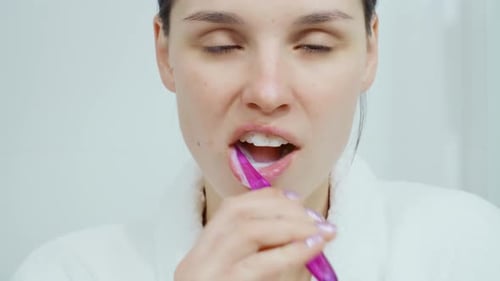 Woman Brushing Teeth in Bathroom in the Morning