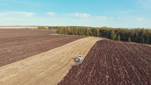 An Autumn Landscape of Fields and Blue Cloudy Sky - Tractors Plows the Field