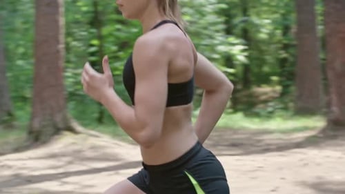 Athletic Woman Jogging Through Green Forest