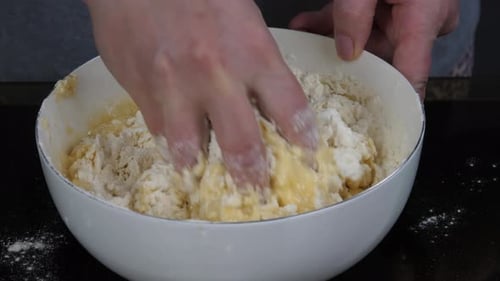 Hands Mixing Dough Ingredients in a Bowl