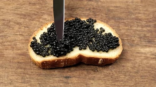 Spreading Black Caviar Onto Bread with Knife