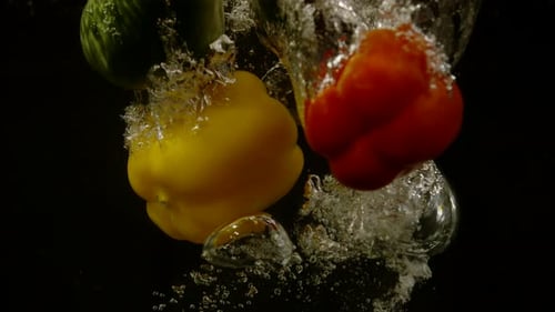 Colorful Bell Peppers Falling Into Water in Slow Motion
