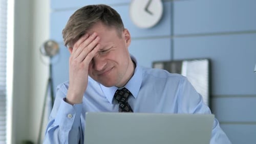 Stressed Businessman Massaging Temples at Desk