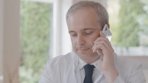 Close-up of Confident Male Doctor Talking on the Phone. Portrait of Professional Physician