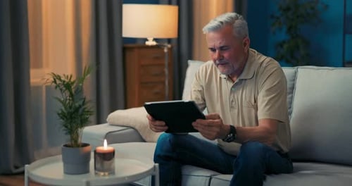 Man Sitting on Couch in Living Room Happy with Online Shopping