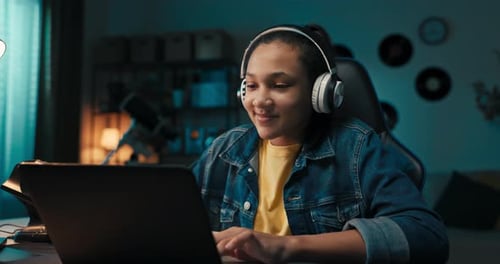 Teenager Studies Diligently in Front of Laptop Takes Notes with Pencil in Notebook Rewrites Listens