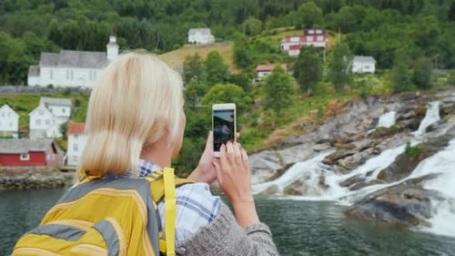 Traveler Photographs a Picturesque Landscape in Norway, a Waterfall and Traditional Norwegian Houses