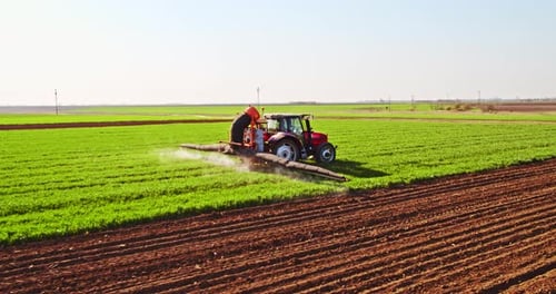 Tractor spraying pesticides on agricultural field