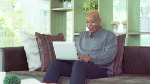 Man Using Laptop Computer on Living Room Couch