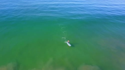 Aerial drone uav view of a SUP stand-up paddleboarder surfing.