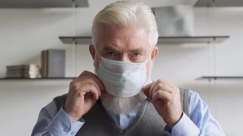 Close Up Portrait Elderly Man Puts a Medical Mask on His Face To Protecting Yourself From