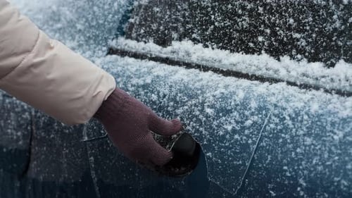 Hand Clears Snow off Blue Car in Winter