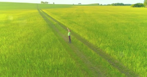 Sporty Child Standing in Green Wheat Field with Raised Hands Up