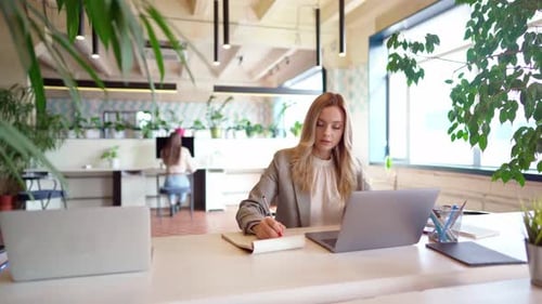 Young Businesswoman in Formal Suit Working at the Table in Modern Open Space Office