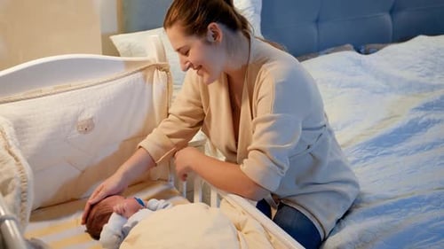 Mother Soothing Baby Lying in Crib at Home
