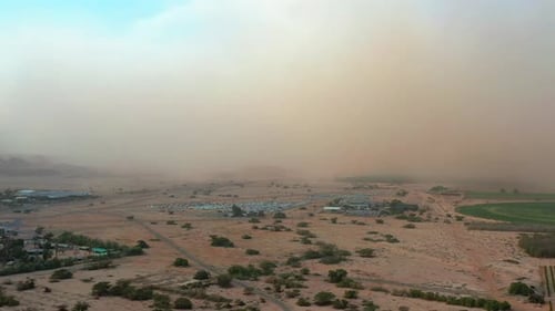 Large dark sandstorm moves over Timna Park in the Negev Desert as the sky above the storm is a brigh