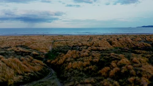 Aerial low view over marram grass anchored dunes at sunset.